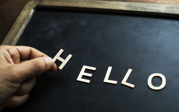 Image of a hand placing letter to spell the word 'hello' onto a chalk board
